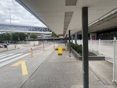 Sheltered walkway next to airport terminal and shuttle bus pickup area.