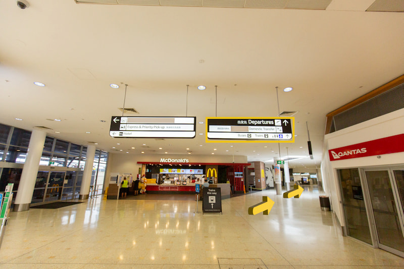 Airport hallway with McDonald's and yellow arrows pointing left.